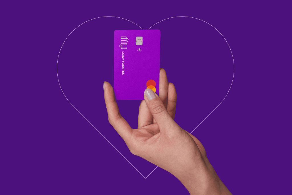 Mano sostiene tarjeta de crédito Nu dentro de un corazón rosa. En Nu México estamos EnaMorados de nuestros clientes