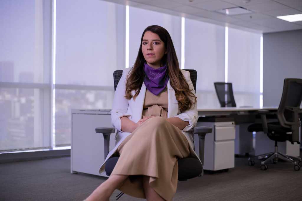 Michelle Naranjo en las oficinas de Nu México, vestida con un saco blanco y una pañoleta morada que muestra su empatía en el día internacional de las mujeres