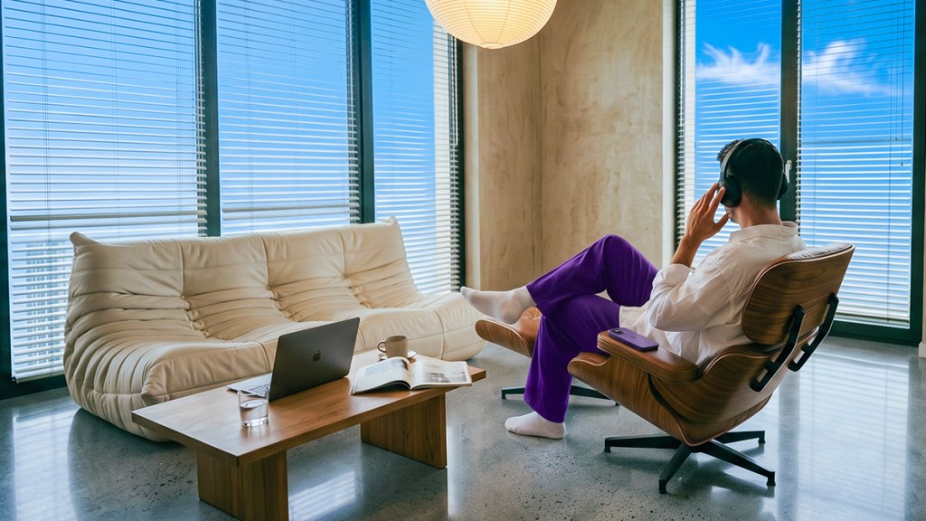nu-sucursales_ Header Persona cómoda en su casa con vista a la ciudad, trabajando desde cualquier lugar con su laptop, ilustrando por qué Nu no tiene sucursales: acceso desde donde quieras sin necesidad de ir a una oficina