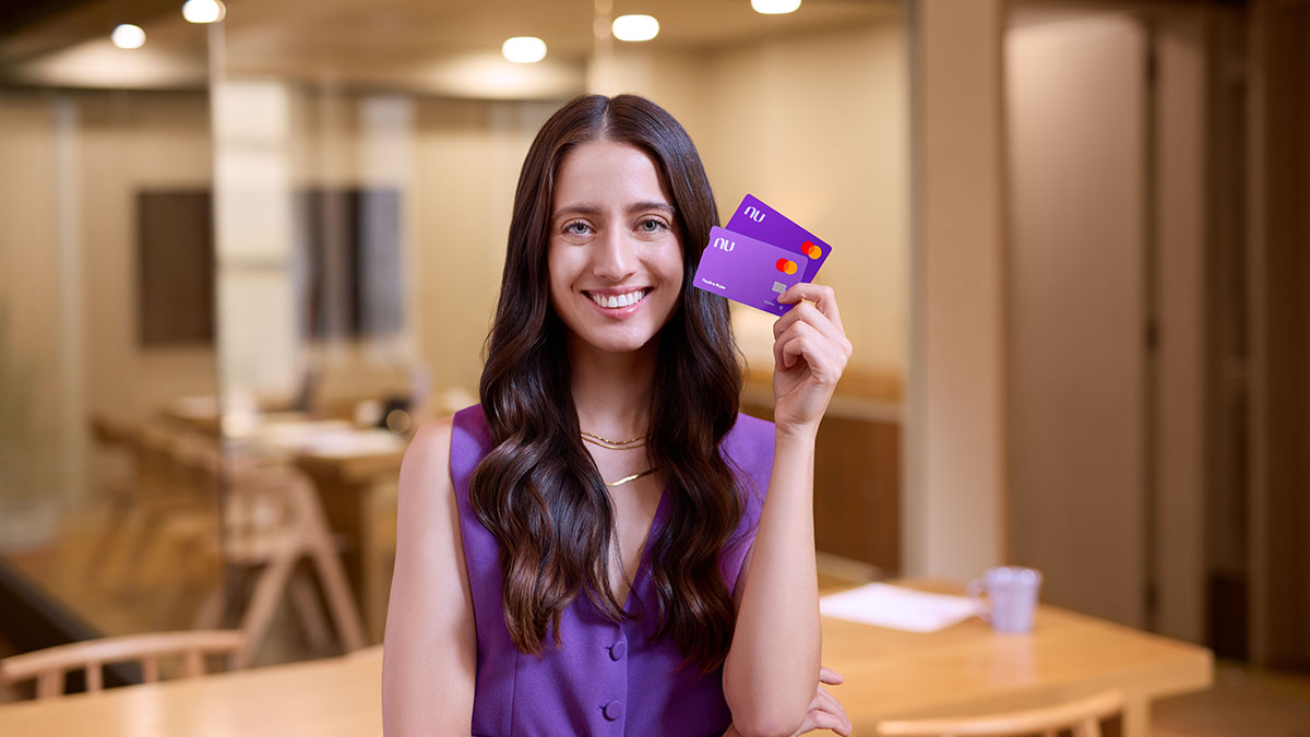 Mujer joven sostiene dos tarjetas Nu en la mano izquierda a la altura de su rostro