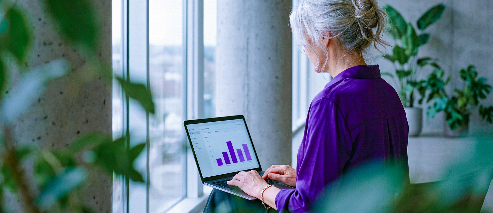 Persona analizando gráficos financieros morados en su laptop ante una ventana con vista a la ciudad, ilustrando cómo empezar con inversiones para principiantes: Cajitas Nu, CETES, fondos de inversión y ETFs desde $100.