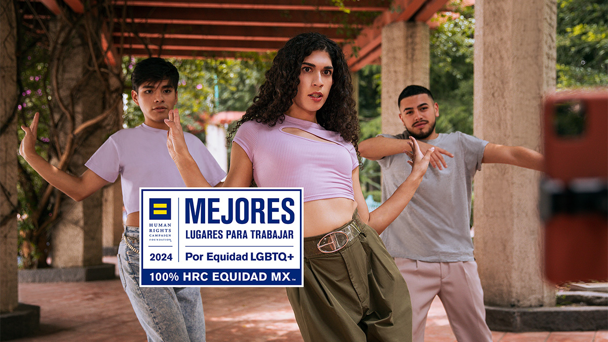 Tres chicos en sus veintes vestidos con ropa casual en colores claros y pertenecientes a la comunidad LGBTQ+ bailan en la pérgola de una jardín anunciando que Nu México es uno de los mejores lugares para trabajar LGBTQ+ en México este 2024