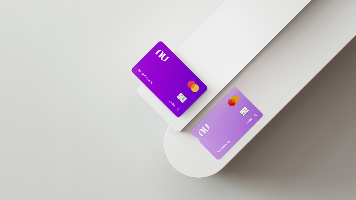 Una tarjeta de crédito Nu color morada reposa en una plataforma blanca junta a una tarjeta de Cuenta Nu recordando lo fácil que es sacar una tarjeta nu