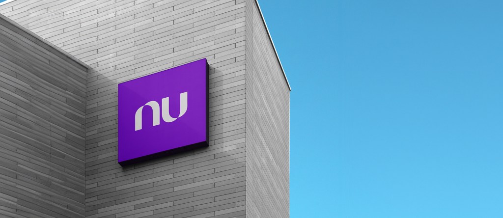 Pared de ladrillos color gris se eleva en un cielo azul para mostrar el logo de Nubank durante sus resultados financieros