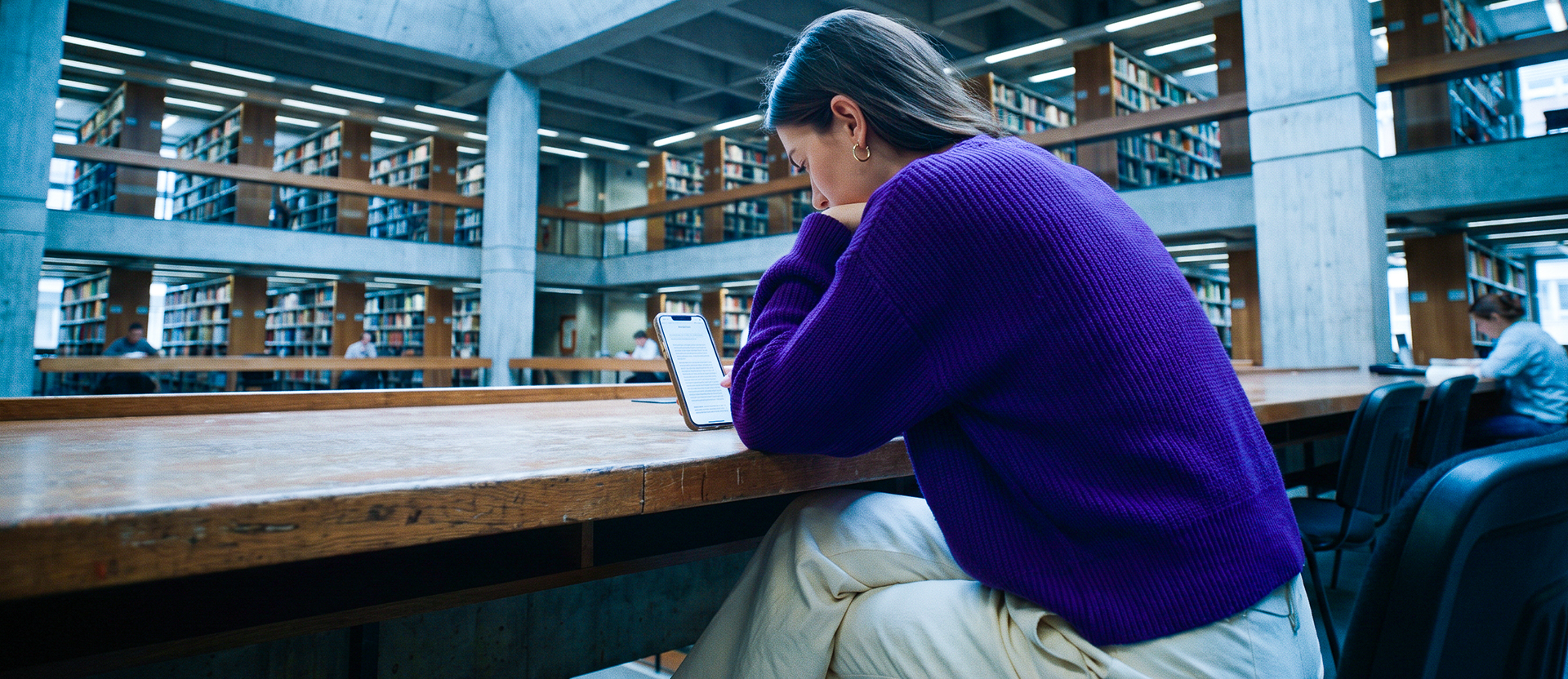 Persona usando su celular en una biblioteca, ilustrando por qué la protección de datos personales es importante en apps y dispositivos donde guardas información.
