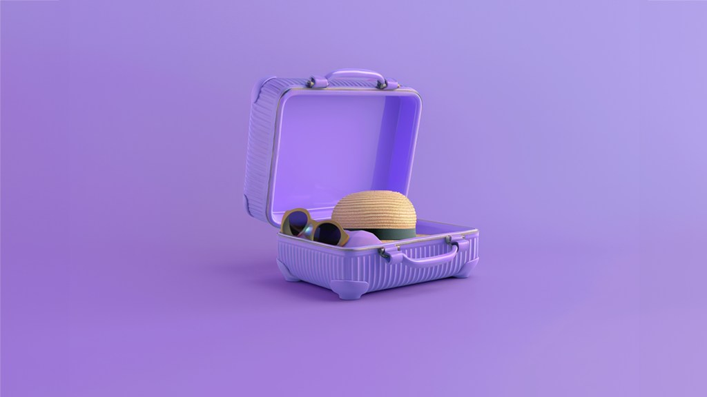 Maleta abierta de color morado exhibe algunos artículos de viaje como gafas obscuras y un sombrero de paja amarillo recordando la importancia de un seguro de viaje internacional