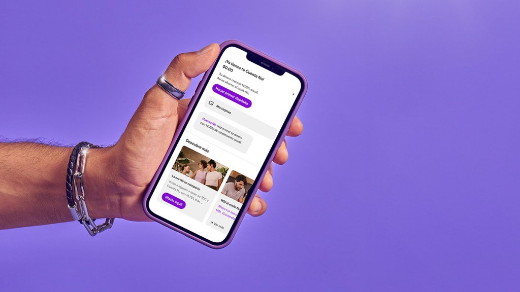 Una mano con anillos y pulseras plateadas muestra un teléfono celular con la app nu abierta