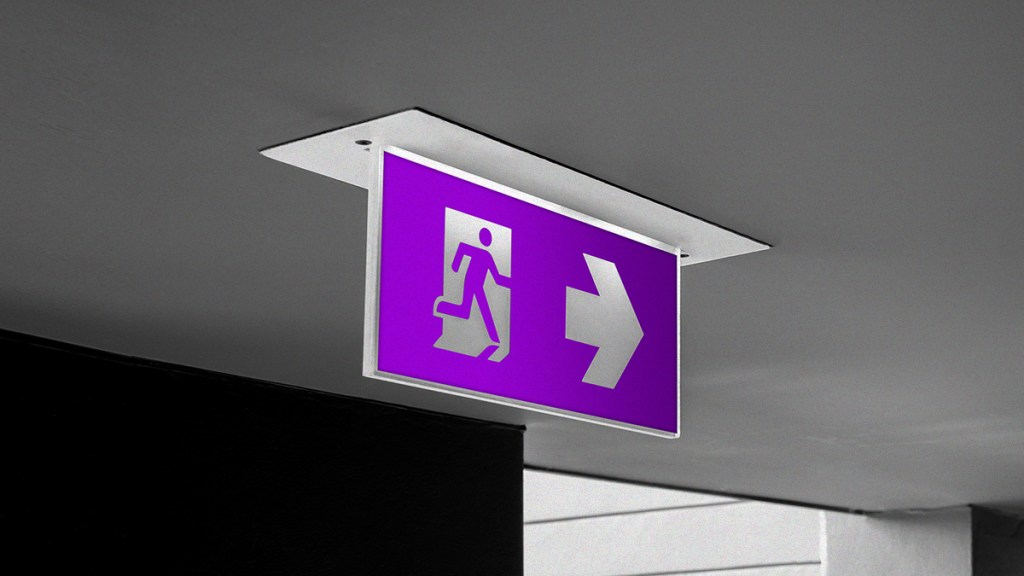 Señaletica de color blanco y morado ubicada en el techo de una oficina indica la salida haciendo una analogía con la frase: ya pagué mi deuda cómo salir del buró de crédito