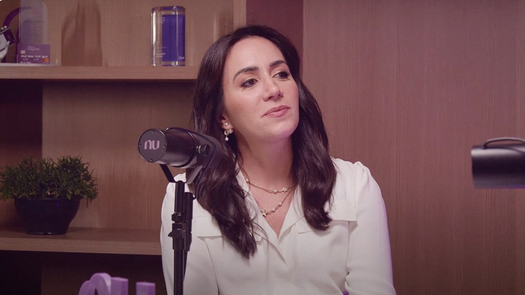 Cristina Junqueira fundadora de Nubank mira hacia el frente mientras le realizan una entrevista en una cabina de radio mientras viste una blusa color blanco de seda mientras habla de la prioridad de negocio en Nu