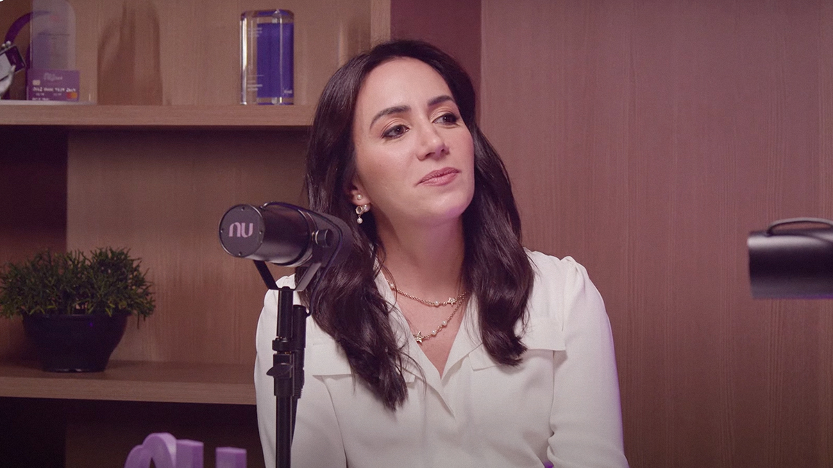 Cristina Junqueira fundadora de Nubank mira hacia el frente mientras le realizan una entrevista en una cabina de radio mientras viste una blusa color blanco de seda mientras habla de la prioridad de negocio en Nu