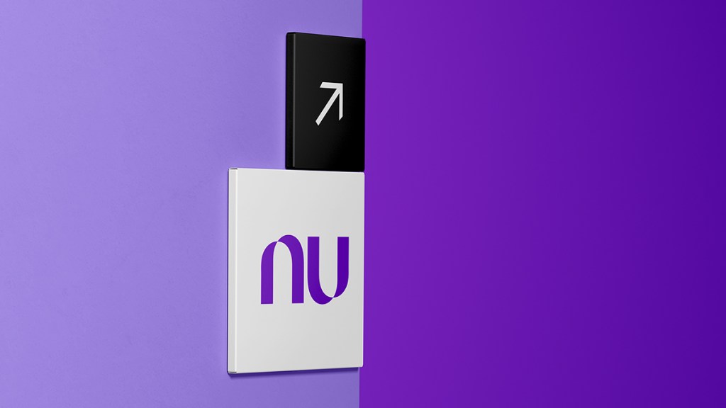 Una señalética de Nu en una pared morada sostiene un indicador de flecha que apunta hacia arriba para anunciar que Nu Holdings Ltd. reporta sus resultados financieros del tercer trimestre del 2024