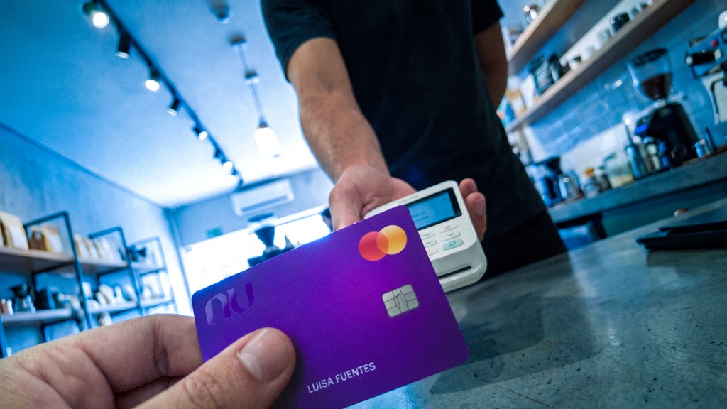 Persona pagando con su Tarjeta de Crédito Nu en una terminal de pago en un comercio, ilustrando qué hacer cuando te cobran comisión por pagar con tarjeta: es ilegal y tienes derechos