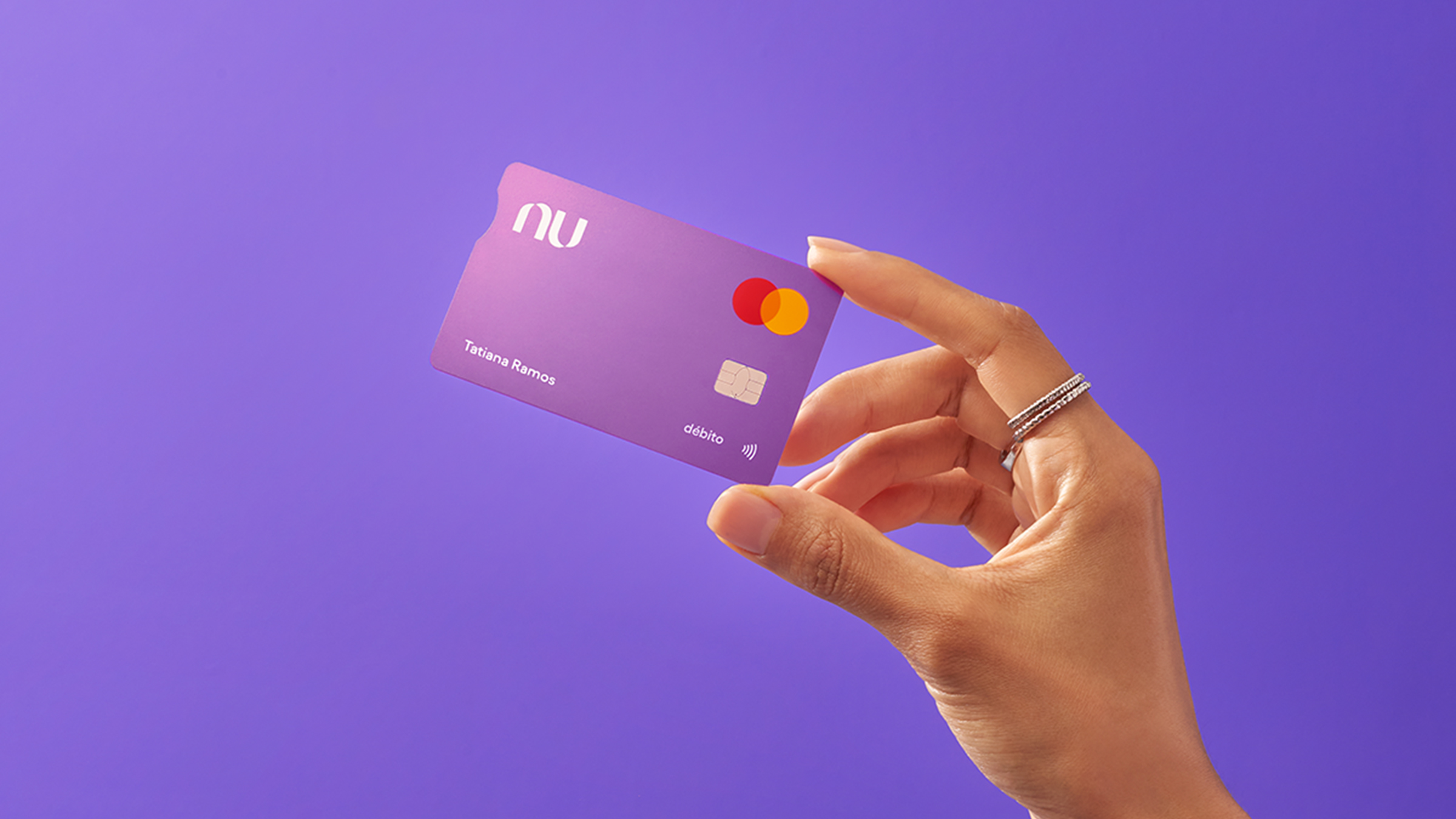 mano sostiene tarjeta de crédito nu ientras se hace un pequeño reflejo en la esquina de la tarjeta morada