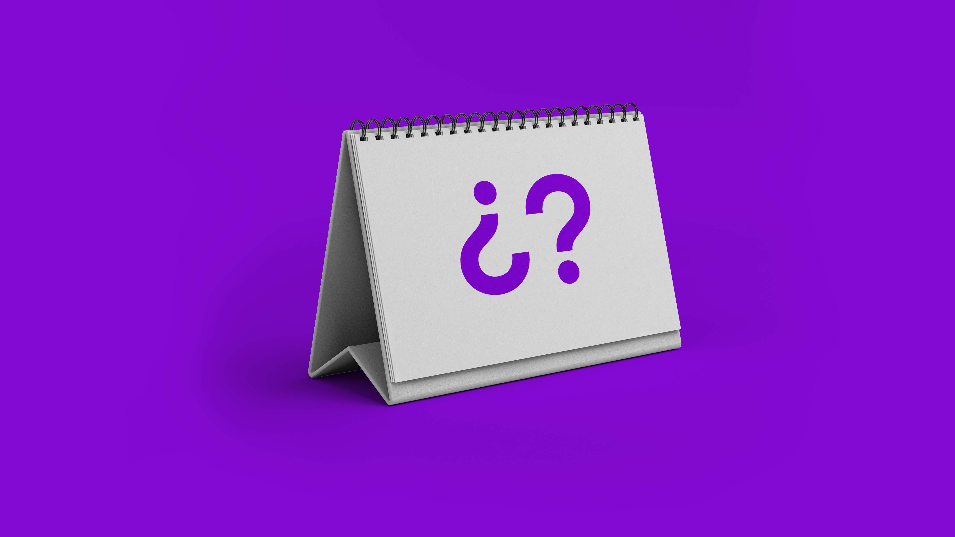 Un calendario de escritorio con las páginas en blanco muestra un par de símbolos de interrogación color morados preguntando cuántos días tengo para pagar después de mi fecha de corte con la tarjeta de crédito nu