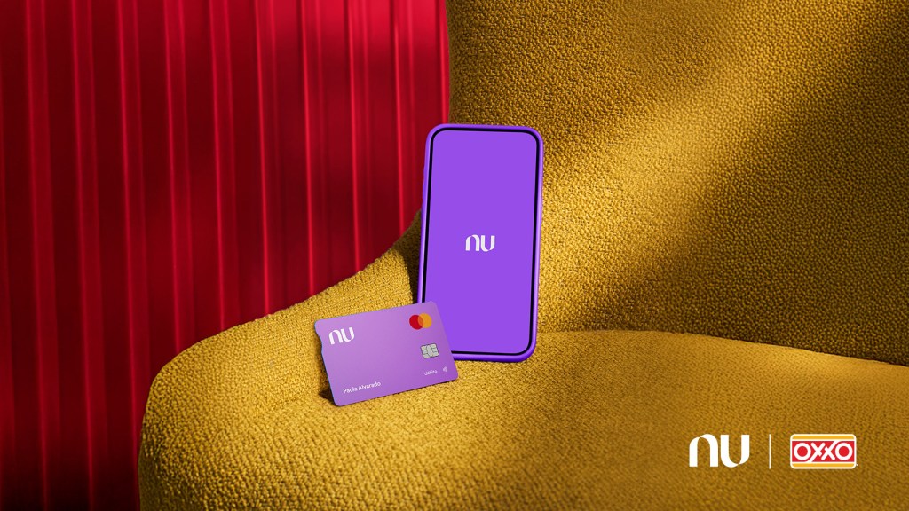 Una tarjeta de débito de color morado reposa junto a un teléfono móvil con l aplicación nu abierta sobre un sillón color amarillo mostaza frente a una cortina roja plegada para anunciar que se pueden realizar retiros de efectivo en Oxxo con Cuenta Nu de Débito