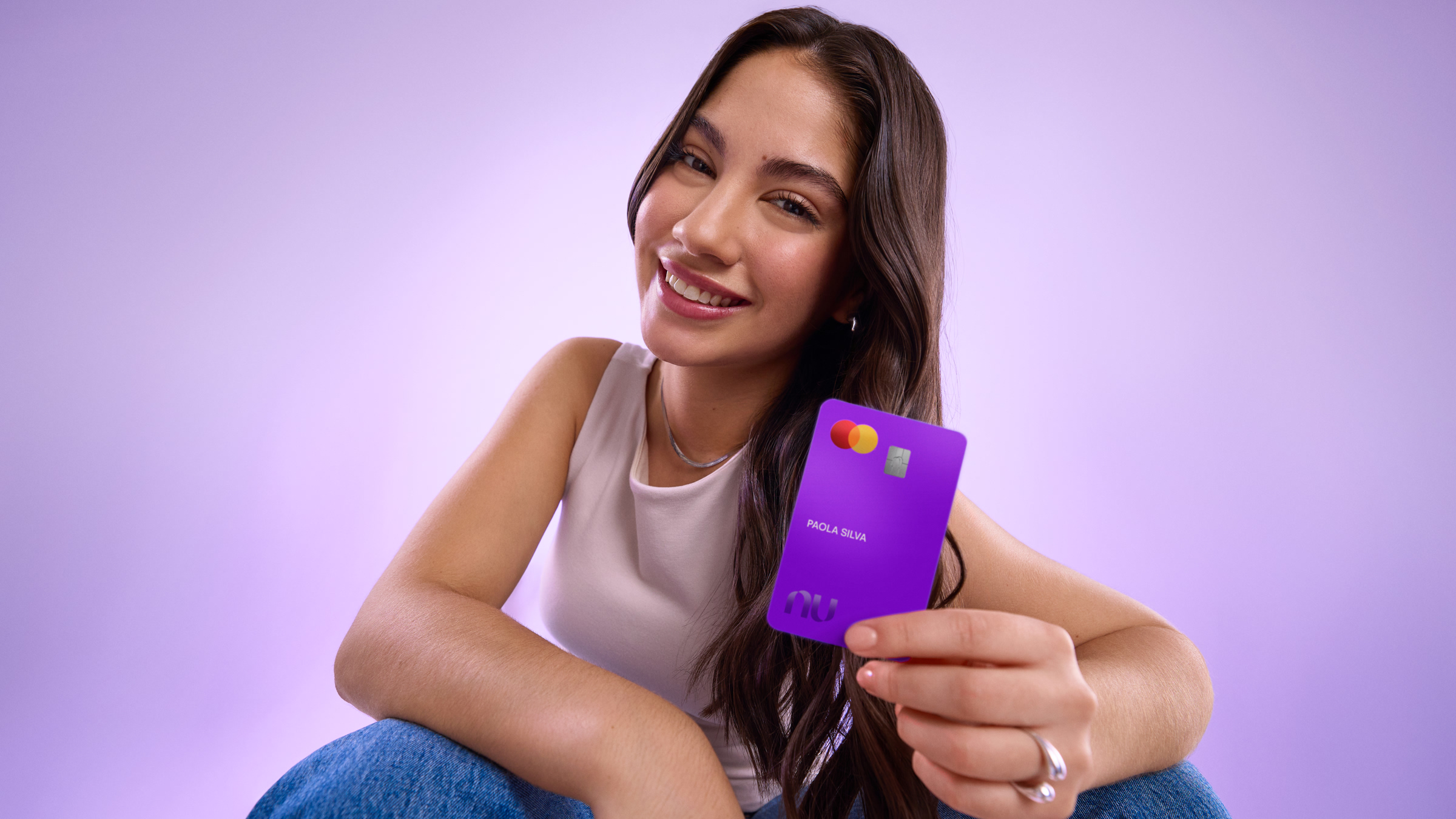 Mujer sonriendo mientras sostiene su Tarjeta de Débito Nu, ilustrando la confianza de poder hacer depósitos en Oxxo con tu Cuenta Nu de Débito.