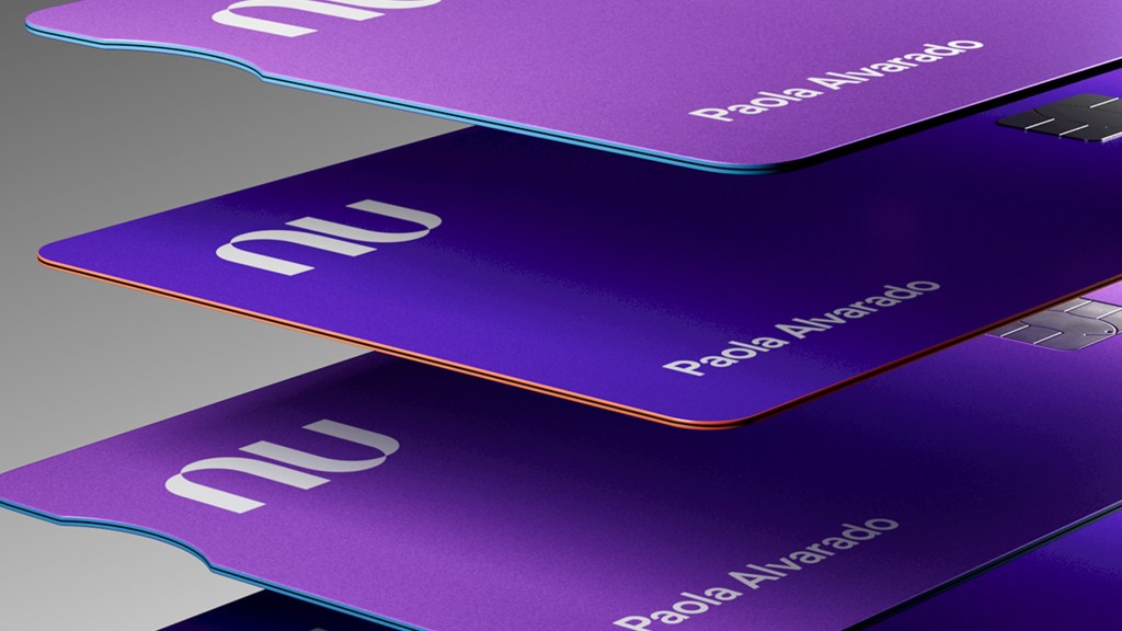 Una pila de tres tarjeta moradas de Nu frente a un nimbo gris llevan a meditar si es mejor pagar con crédito o débito