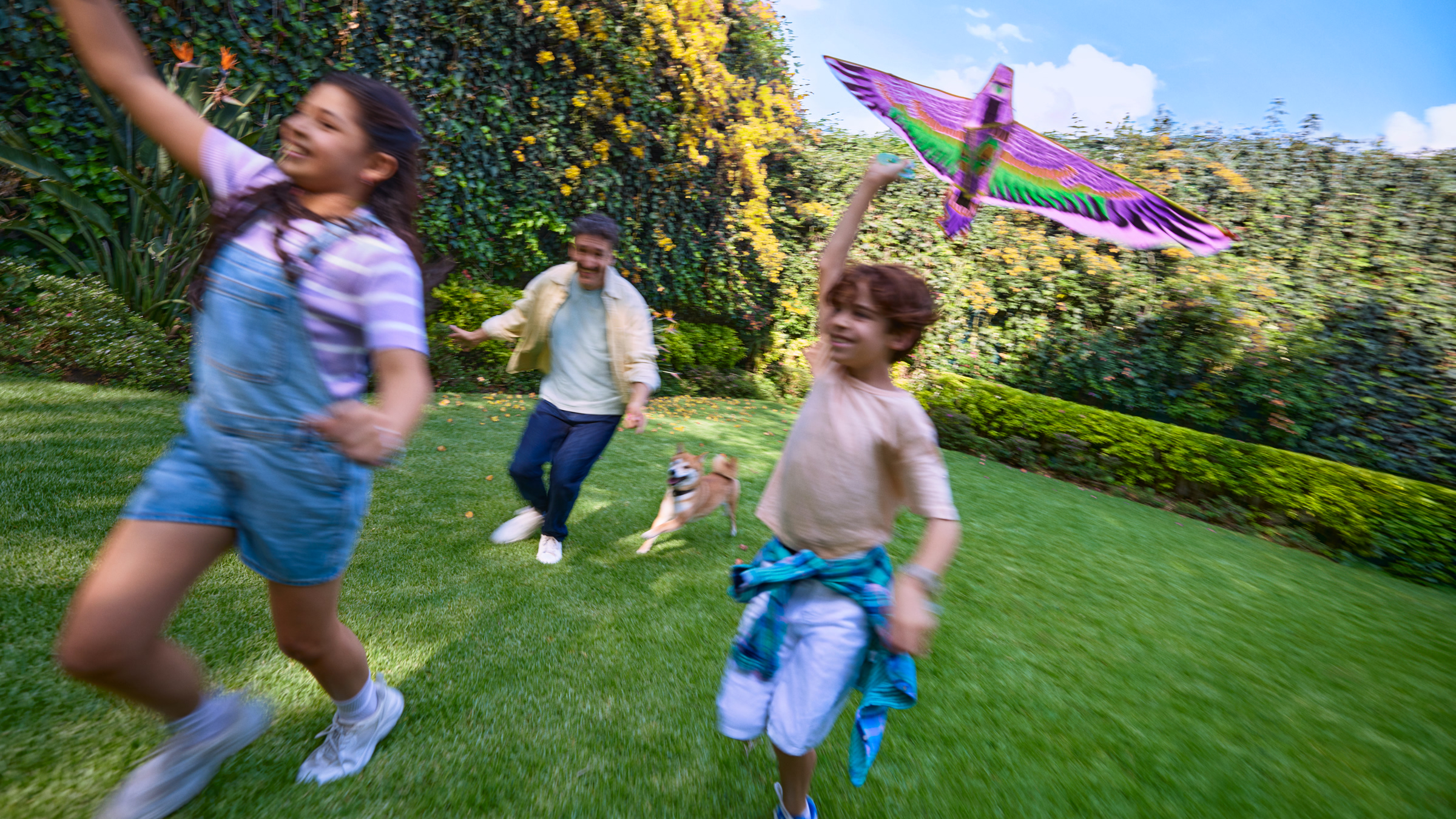 Familia feliz corriendo y volando un papalote en el jardín, reflejando cómo el Préstamo Personal Nu ayuda a cumplir metas y disfrutar momentos en familia.