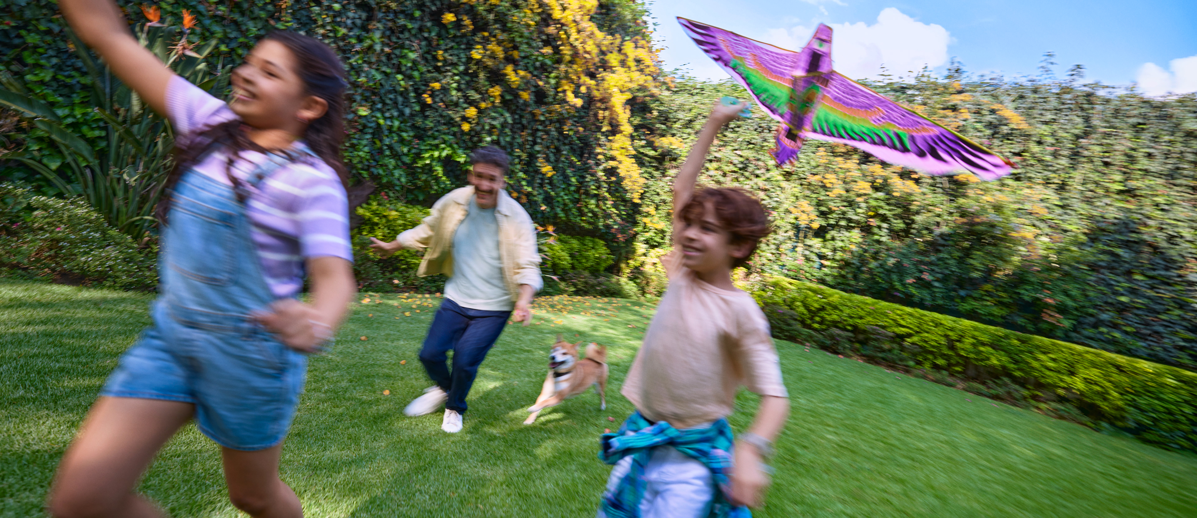 Familia feliz corriendo y volando un papalote en el jardín, reflejando cómo el Préstamo Personal Nu ayuda a cumplir metas y disfrutar momentos en familia.