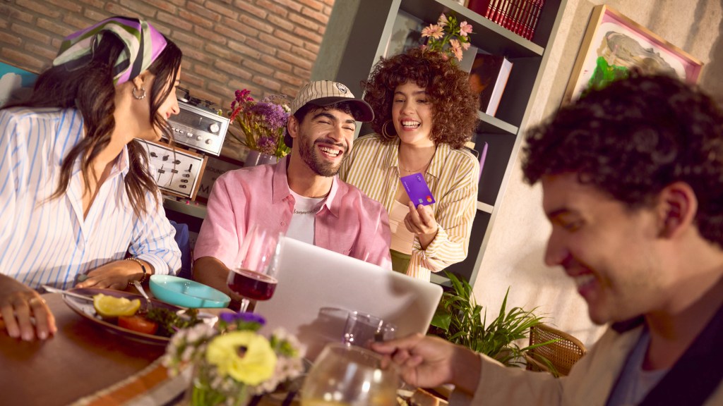Grupo de amigos disfrutando juntos en casa con tranquilidad, reflejando la seguridad de tener tu dinero en Nu con protección de la CNBV y Banxico.
