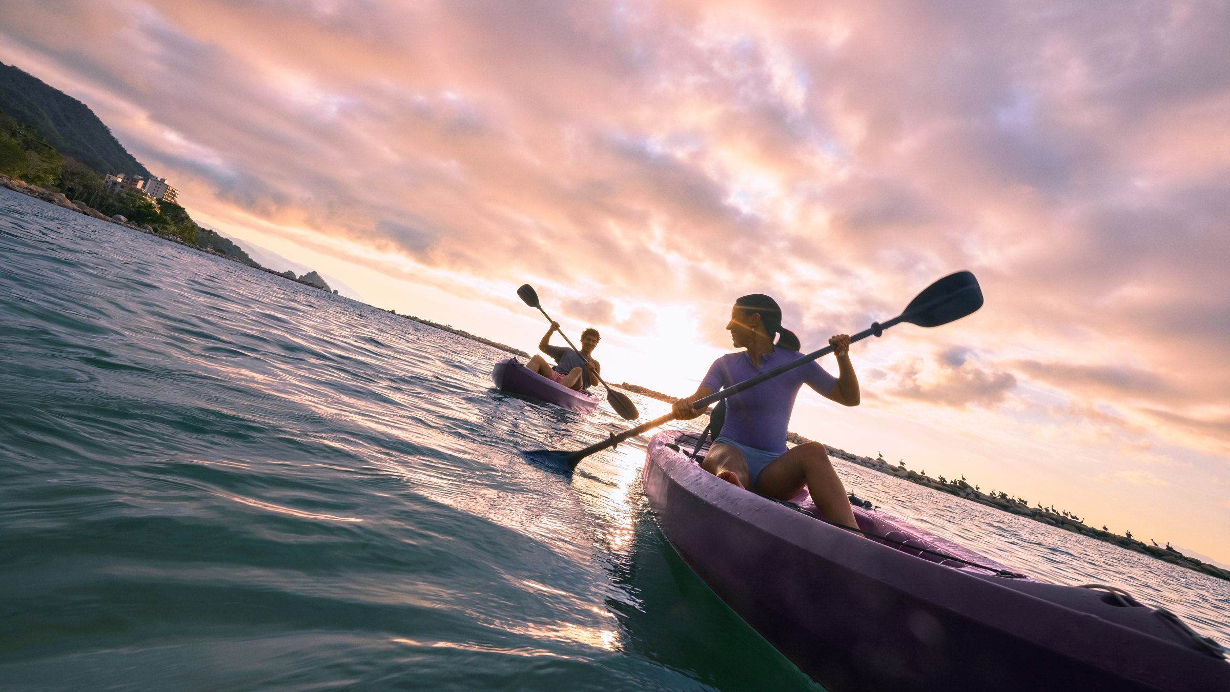 Dos personas en kayak disfrutando un atardecer en un destino de playa, reflejando la libertad de usar Nu en el extranjero durante tus viajes.