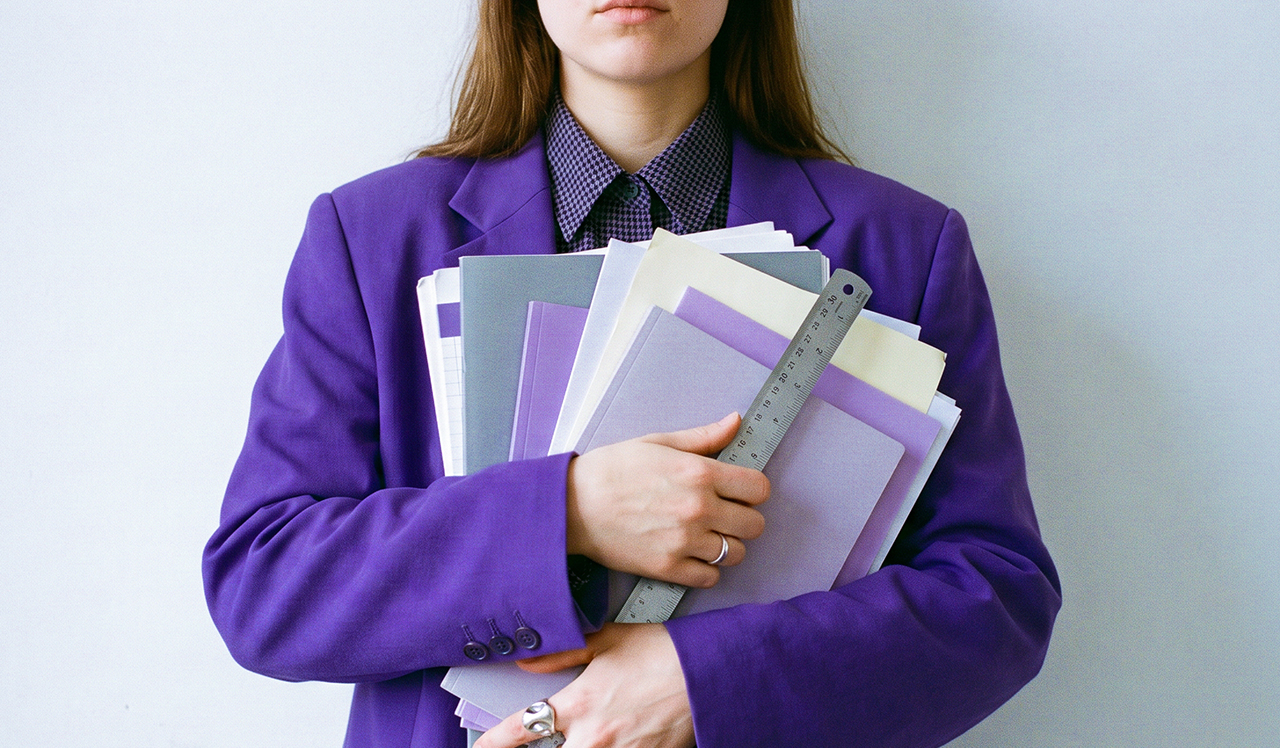 Persona en traje morado sosteniendo múltiples documentos y carpetas, ilustrando el complejo proceso de cómo se obtiene licencia bancaria en México con requisitos de capital y gobierno corporativo.