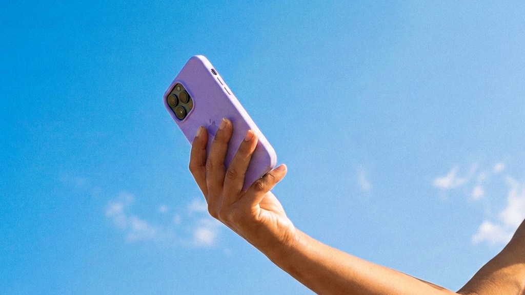 Mano sosteniendo un celular morado contra el cielo azul, ilustrando cómo tener todo tu dinero en un solo lugar con la app Nu: tarjeta de crédito, cuenta de débito, ahorro y préstamo en una sola app.