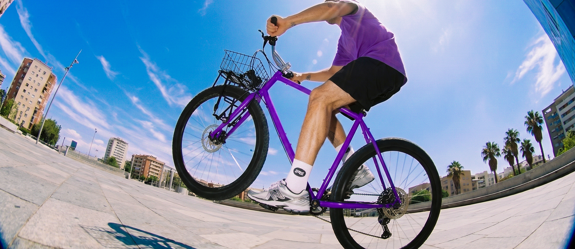 Persona en bicicleta morada avanza con constancia por una plaza soleada, una metáfora de cómo aumentar tu línea de crédito paso a paso con buenos hábitos.