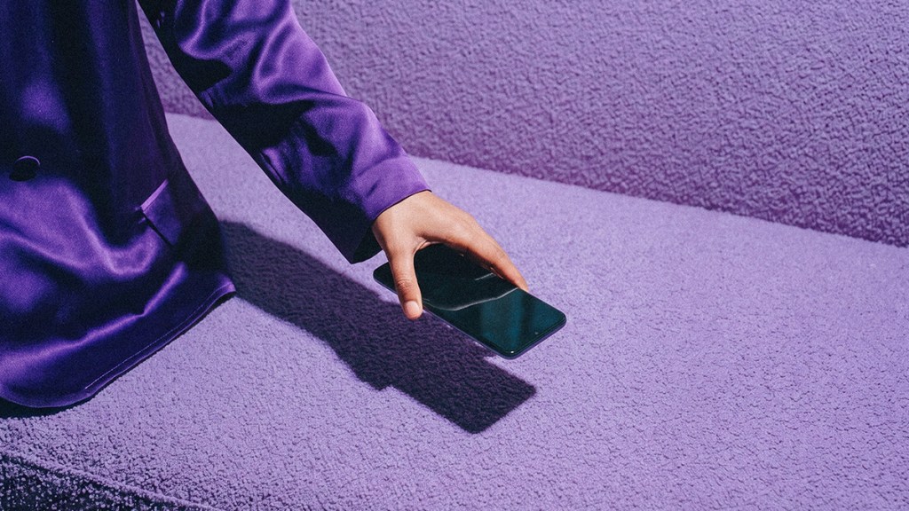 manifiesto-nubank_Header Mano sosteniendo un celular morado Nu contra fondo púrpura, ilustrando el manifiesto Nubank: simplificar dinero sin trámites, filas ni letras chiquitas, dándote control total en tu mano como banco.