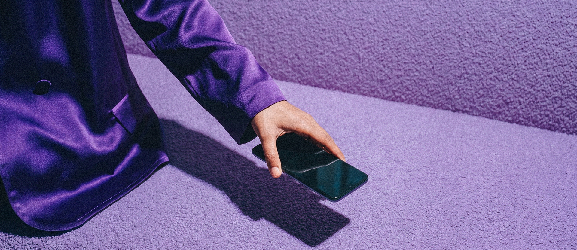 Mano sosteniendo un celular morado Nu contra fondo púrpura, ilustrando el manifiesto Nubank: simplificar dinero sin trámites, filas ni letras chiquitas, dándote control total en tu mano como banco.
